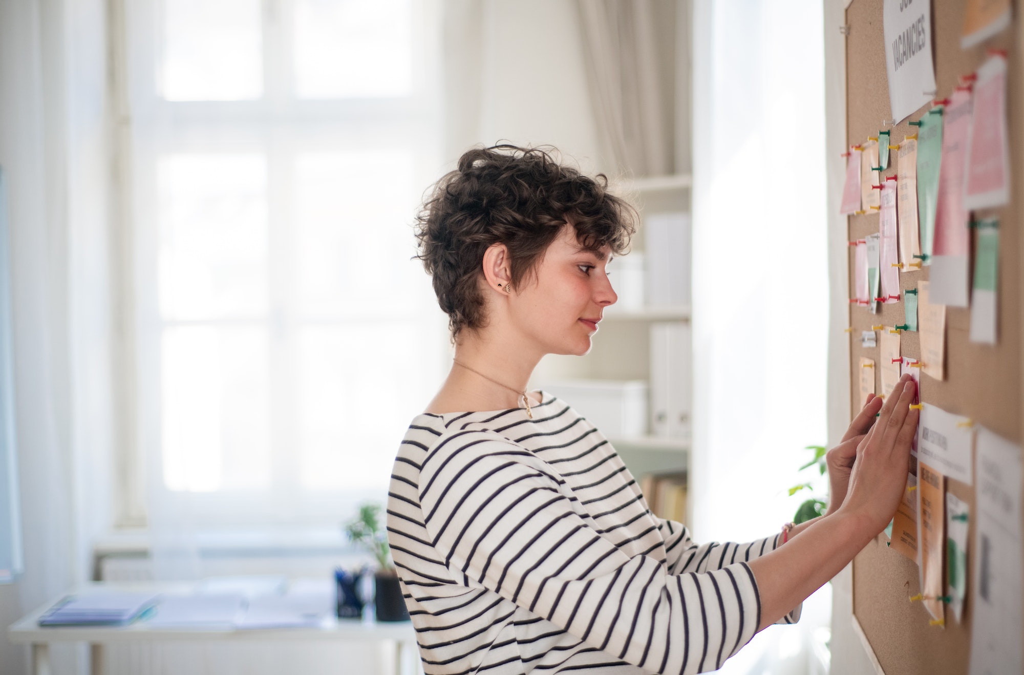 Employé d'une agence pour l'emploi épinglant des offres d'emploi sur un tableau d'affichage.