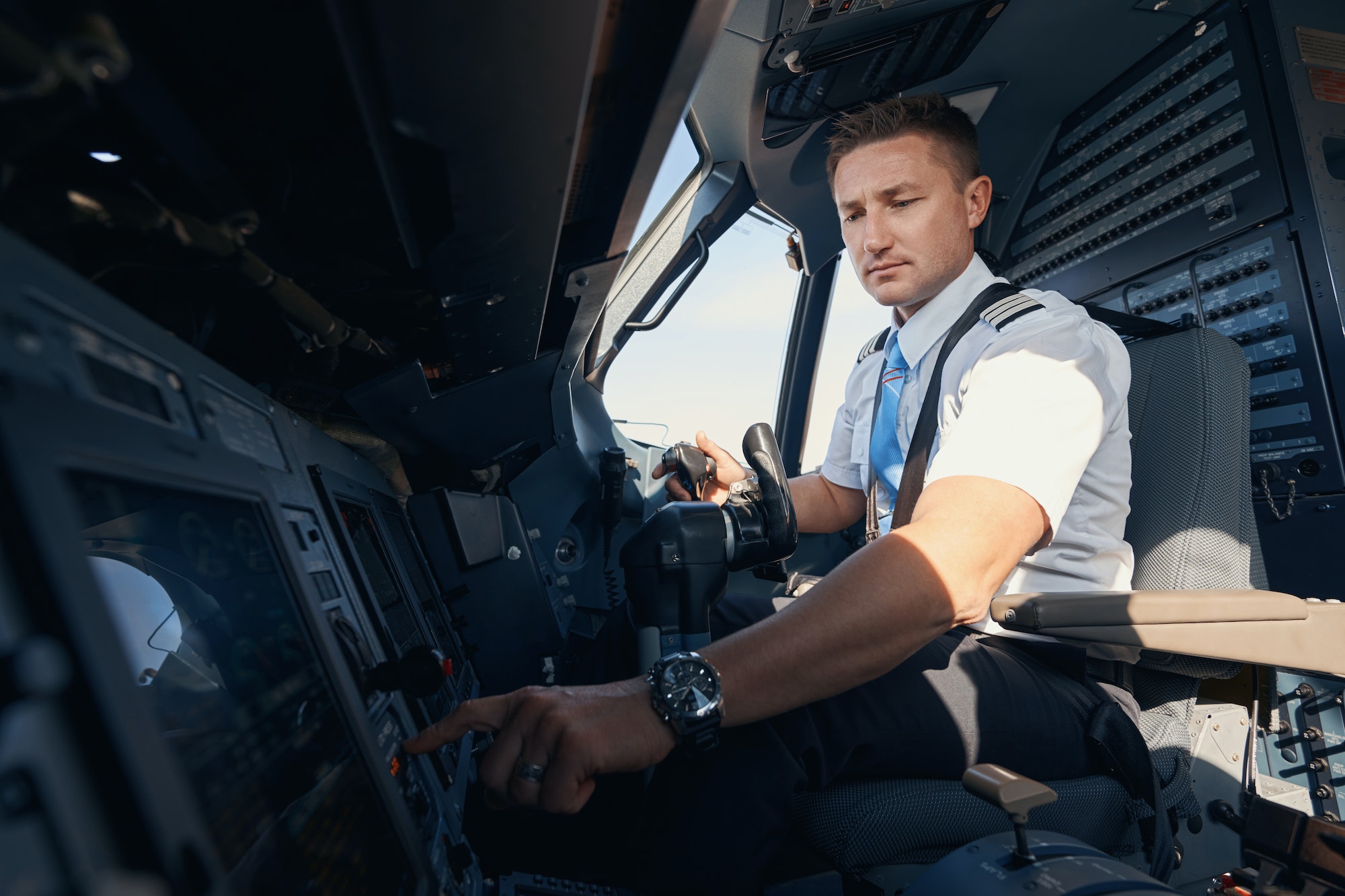 Homme, copilote, appuyant sur un bouton du tableau de commande d'un avion