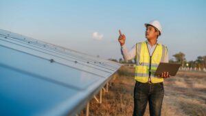 Technicien d’exploitation Energie avec un casque de protection et un gilet jaune avec un ordinateur dans les mains