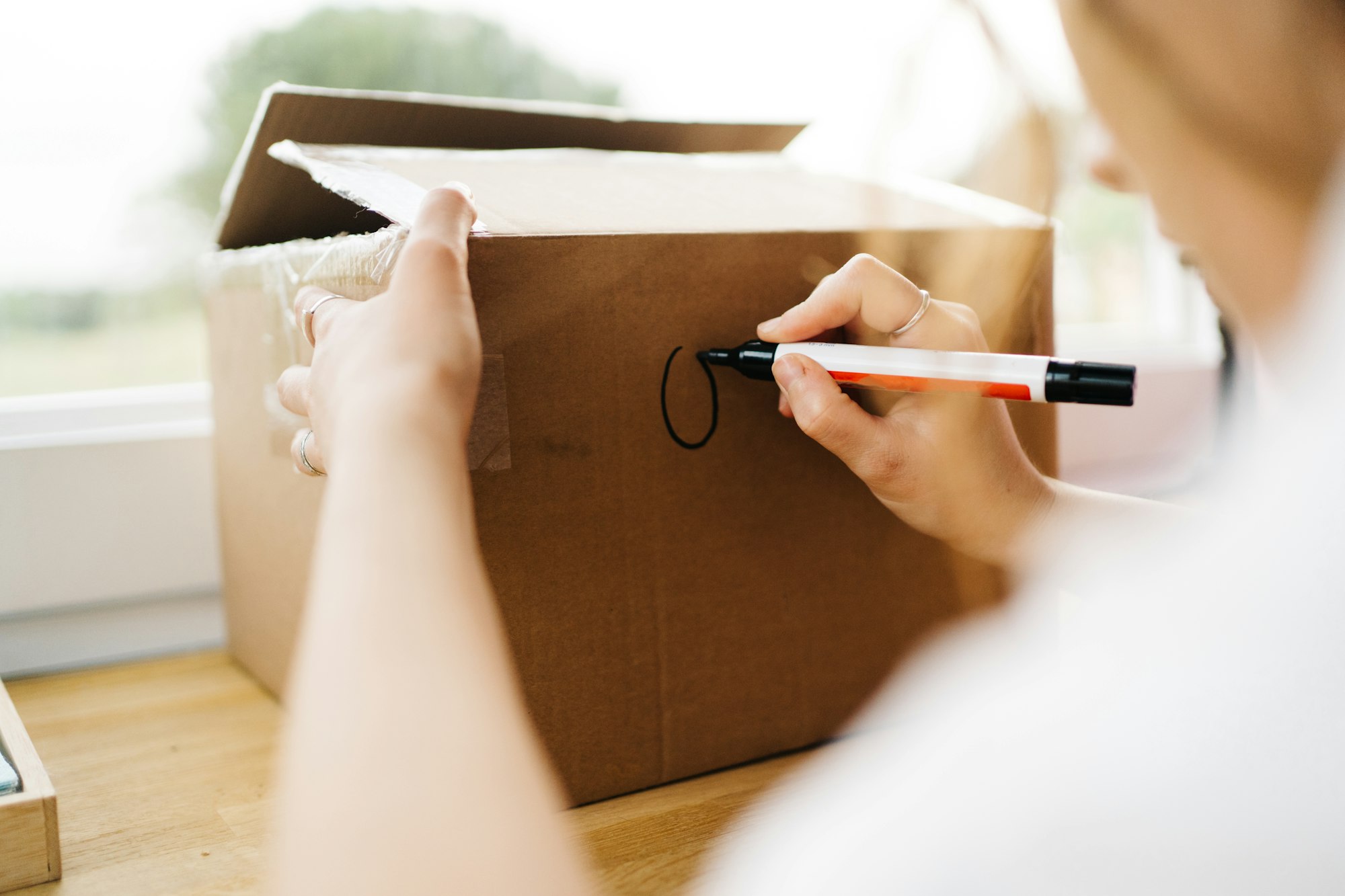 unrecognisable girl writing text on moving box