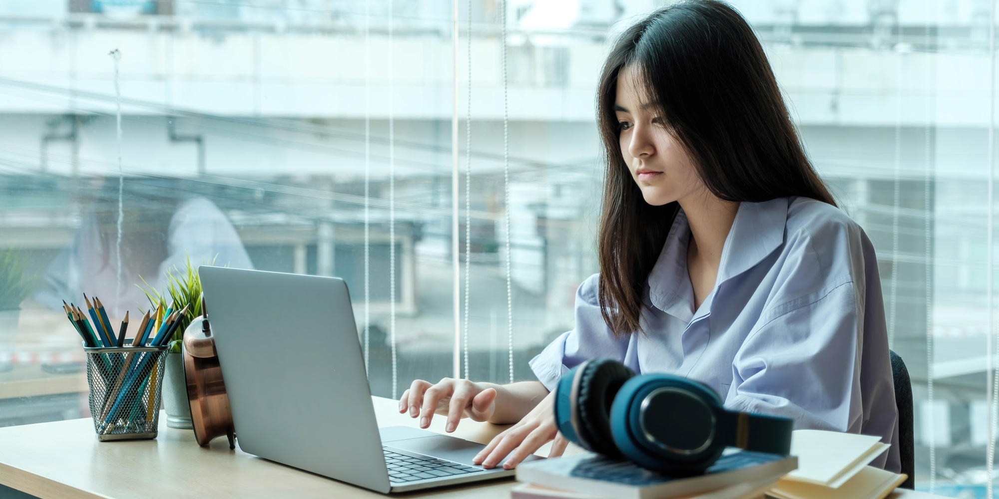 Asian female student taking online class. e-learning. Remote work.
